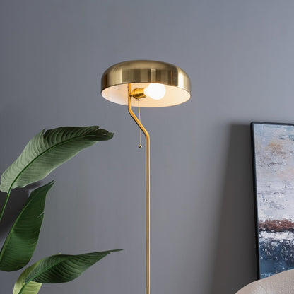 Gold floor lamp against a gray wall with a plant and painting in the background