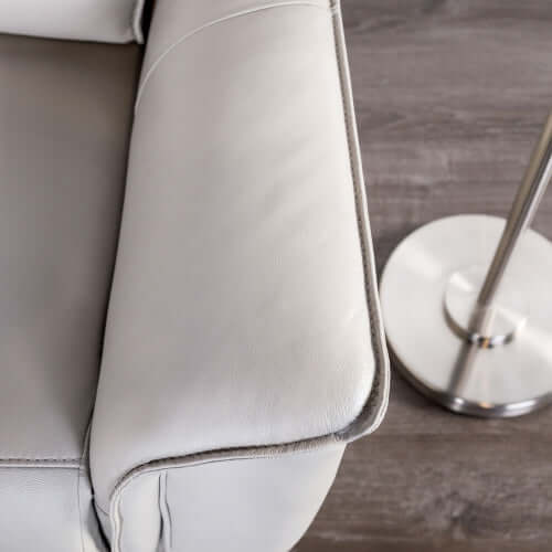 Close-up of a beige recliner chair arm  with a metallic lamp on a wooden floor.