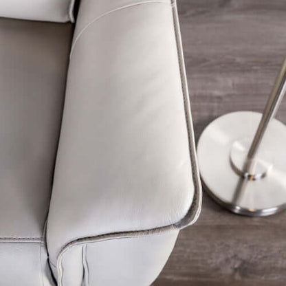 Close-up of a beige recliner chair arm  with a metallic lamp on a wooden floor.