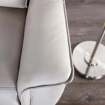 Close-up of a beige recliner chair arm  with a metallic lamp on a wooden floor.