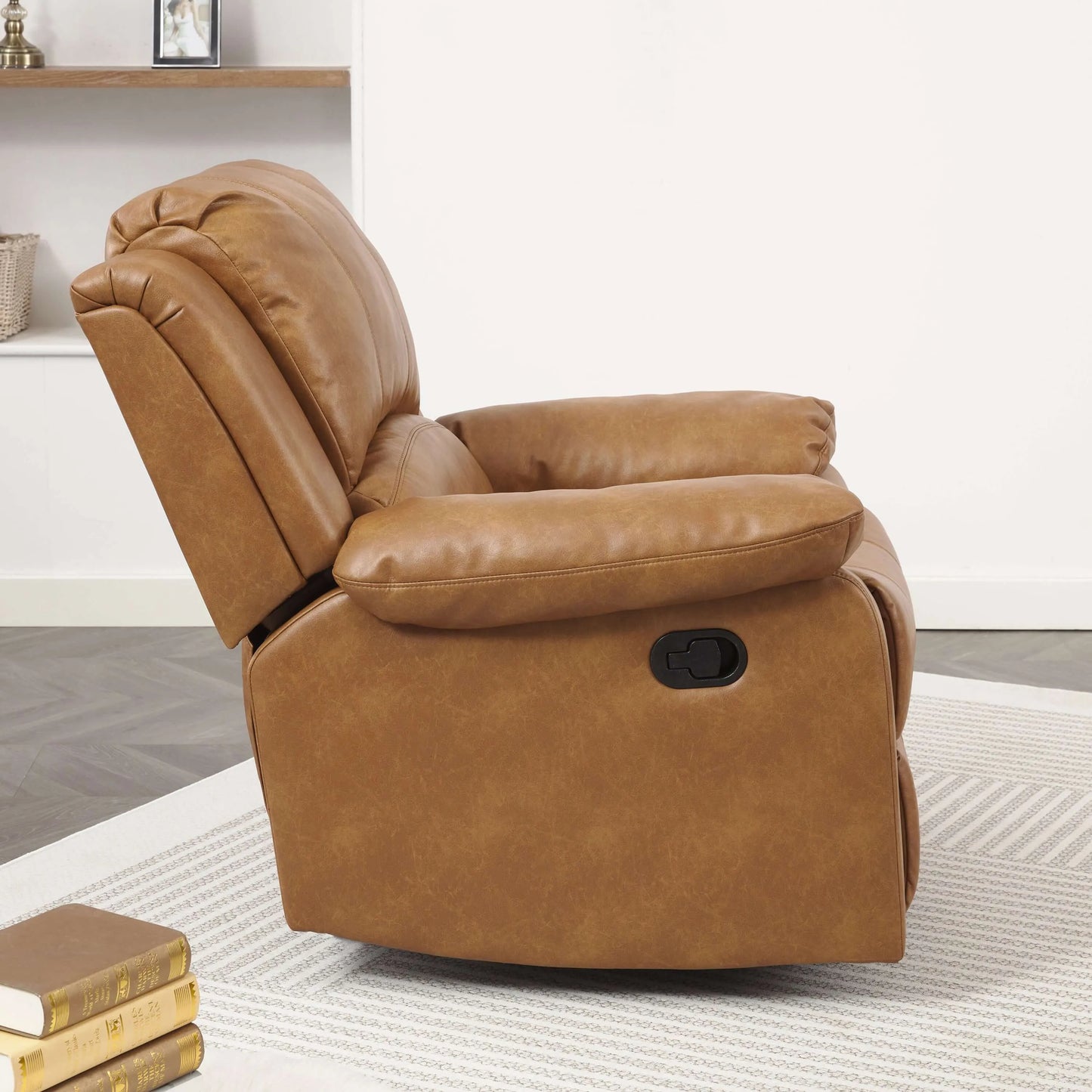 Side view of a brown leather recliner chair with manual pull handle in a room with a book and rug.