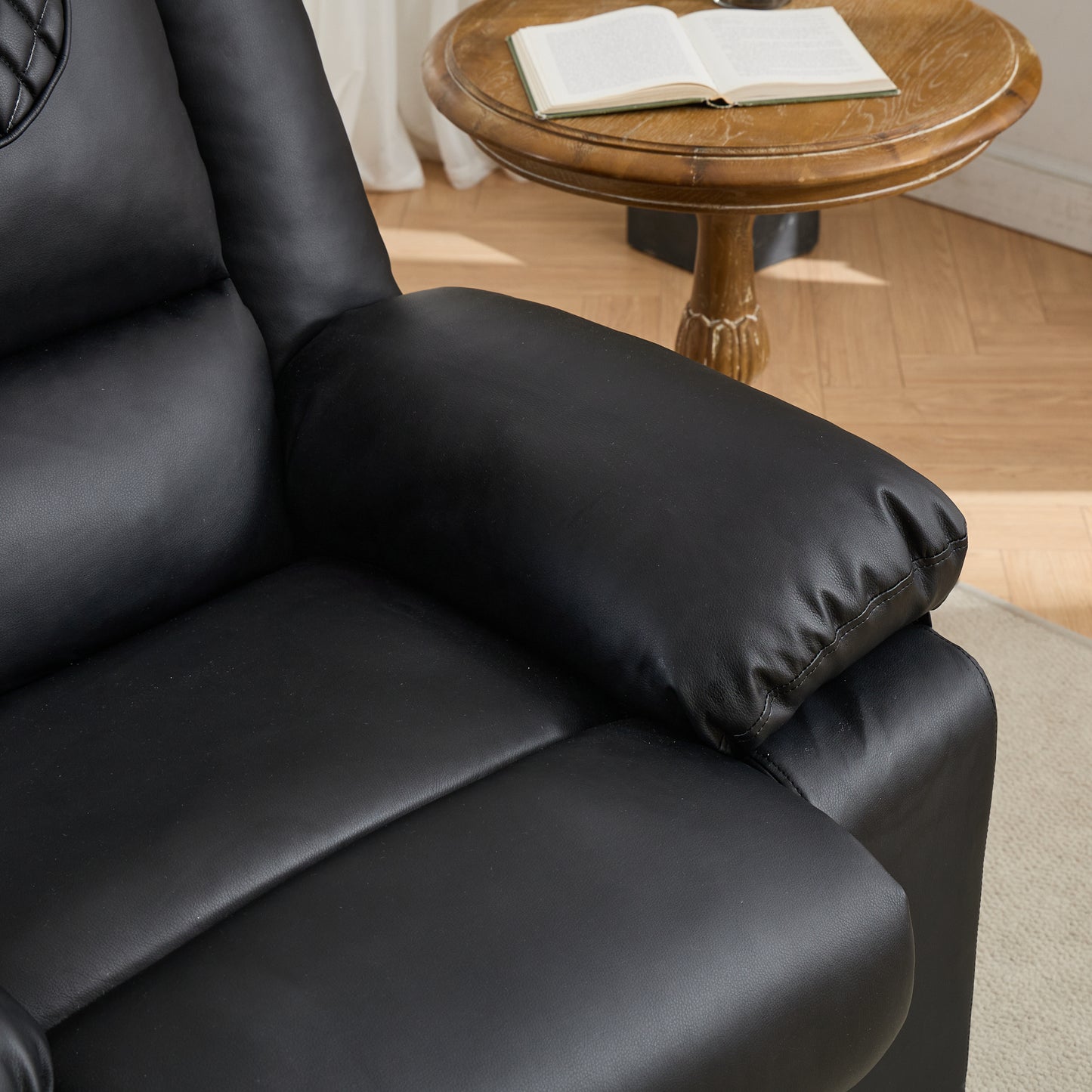 Black leather armchair with a wooden side table and open book in the background