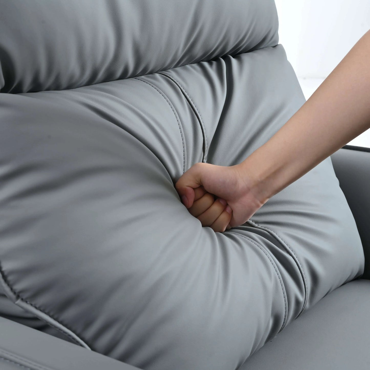 Hand pressing into a gray recliner chair cushion to demonstrate softness