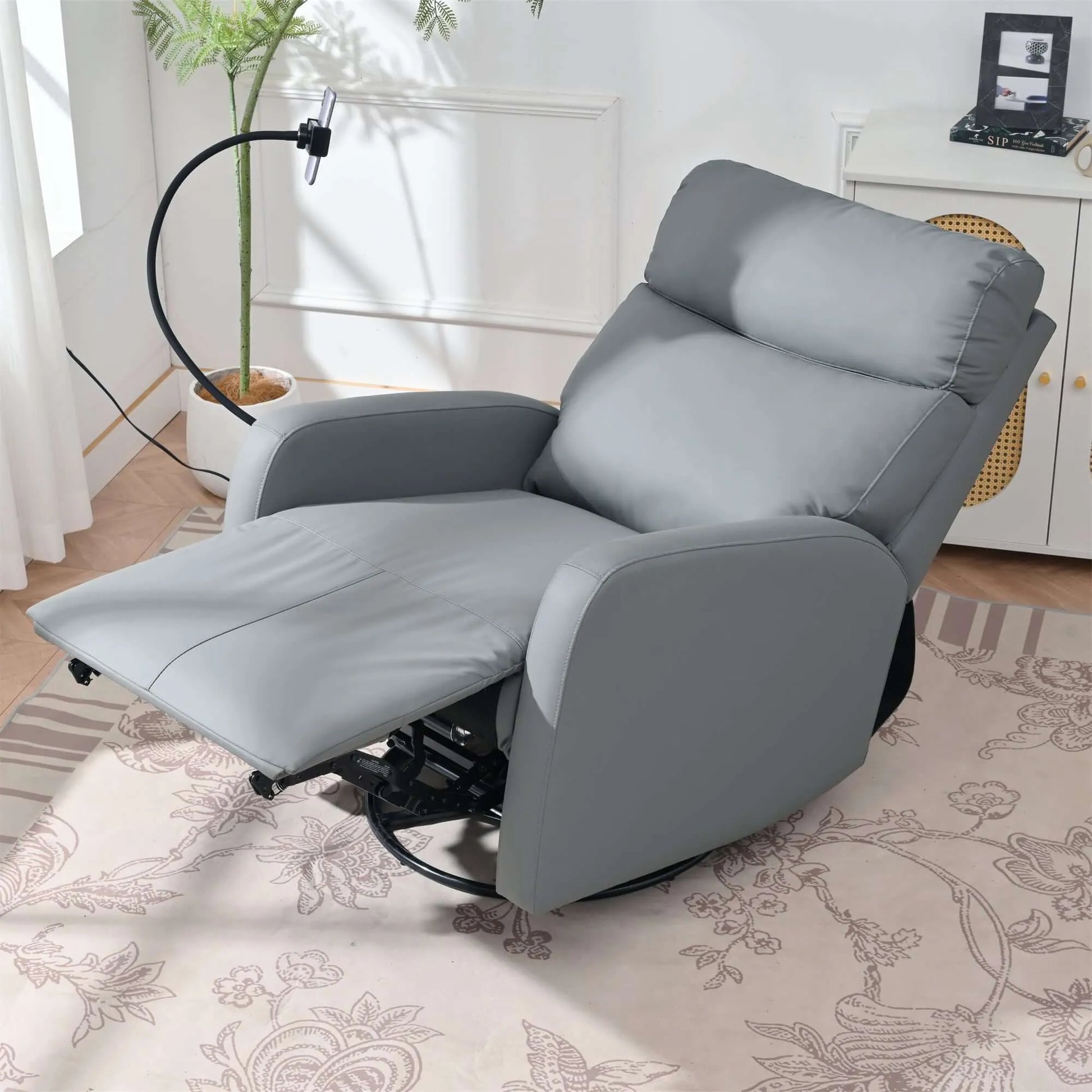 Top view of a fully extended gray recliner chair in a living room setting with a plant and window in the background.