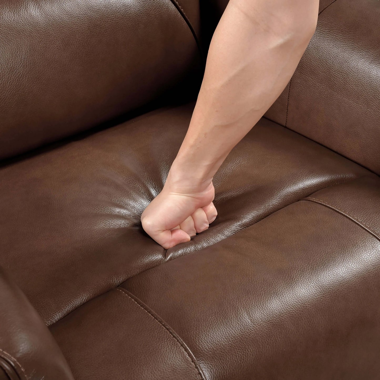 Person's fist on a brown leather recliner chair cushion