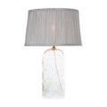 Table lamp with a textured glass base and gray pleated shade on a white background
