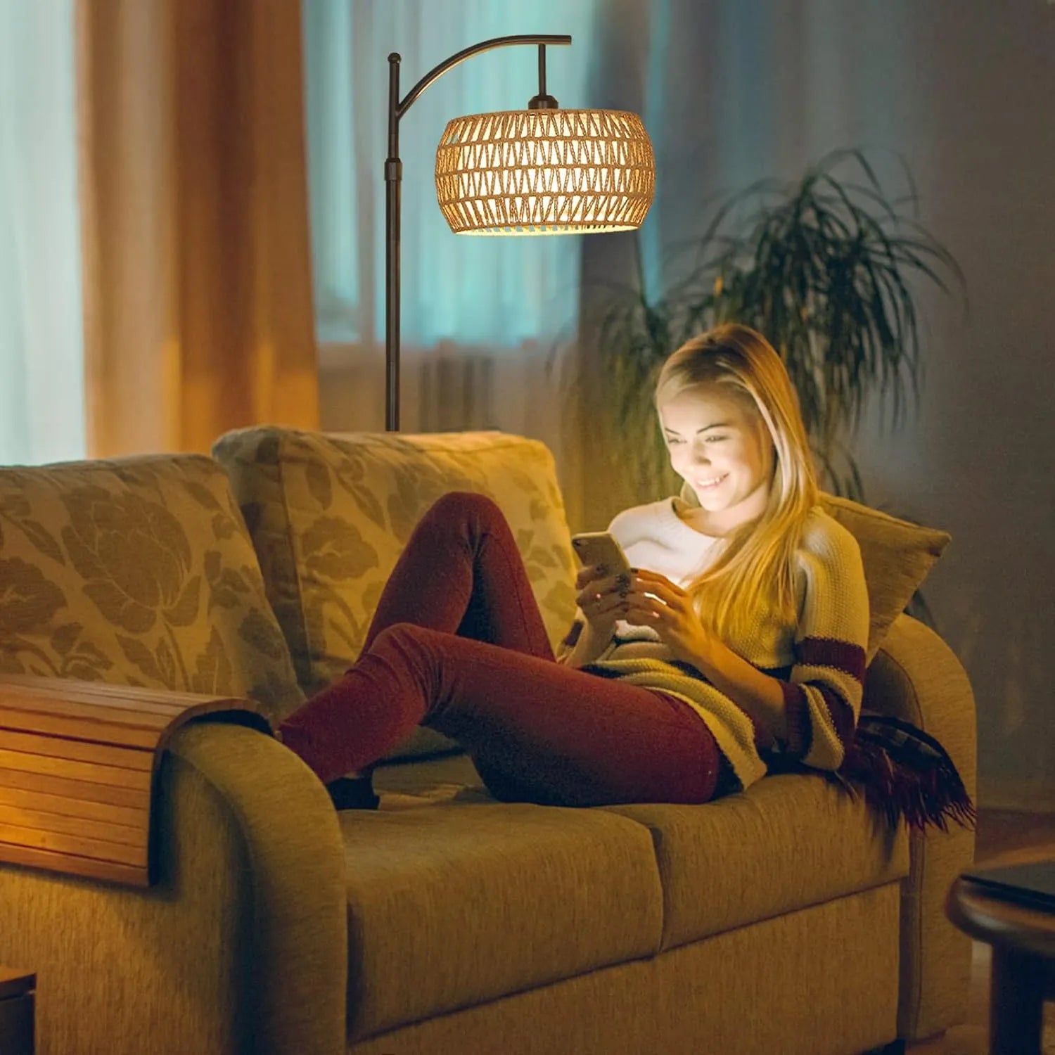 Woman sitting on a couch using a phone in a cozy living room with warm lighting.