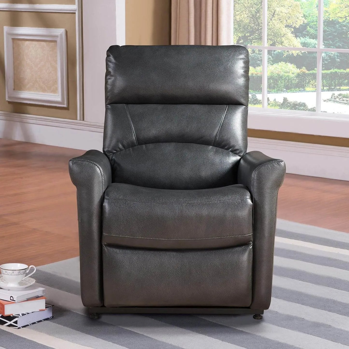 Black faux leather recliner chair in a living room setting with books and a cup on a small table.