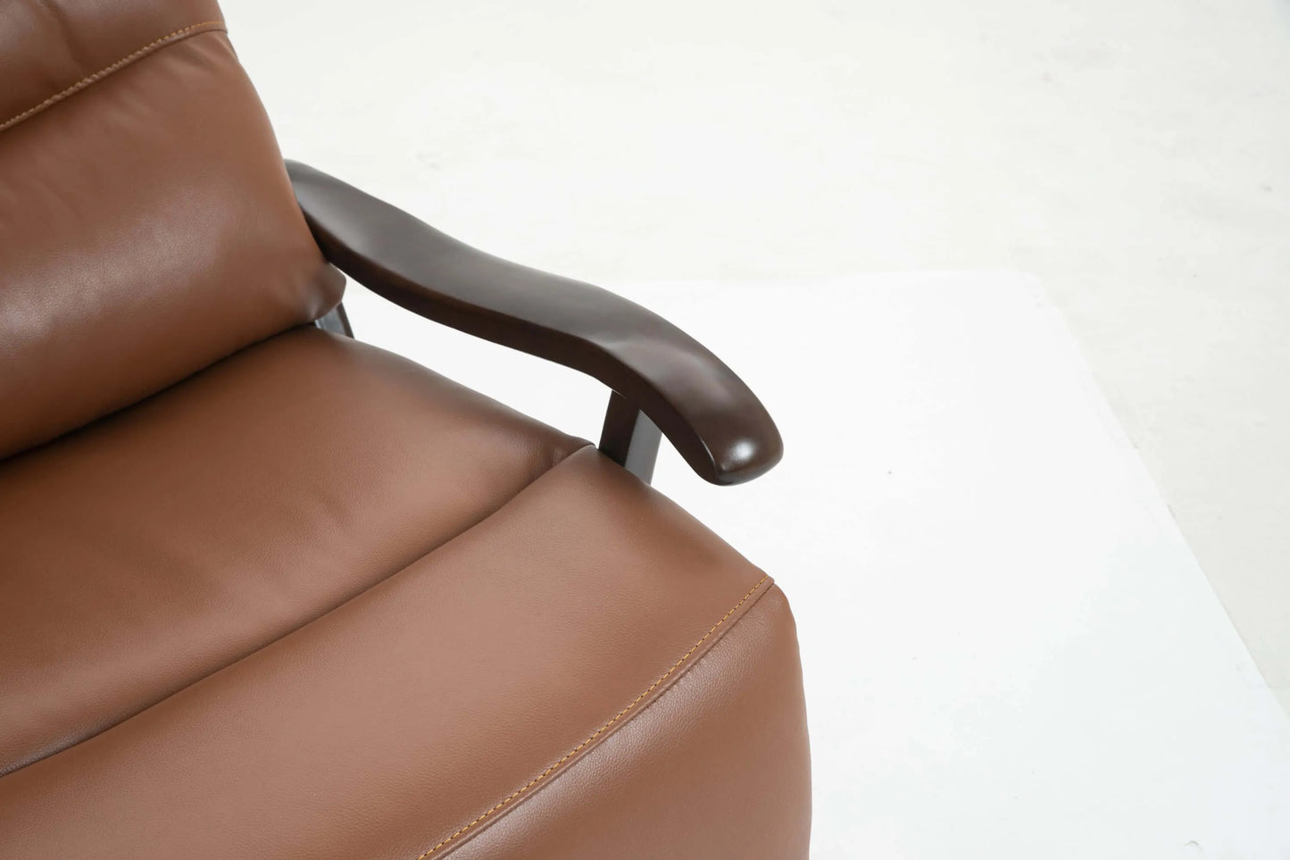 Close up of wooden arms on a brown leather recliner chair on a white background
