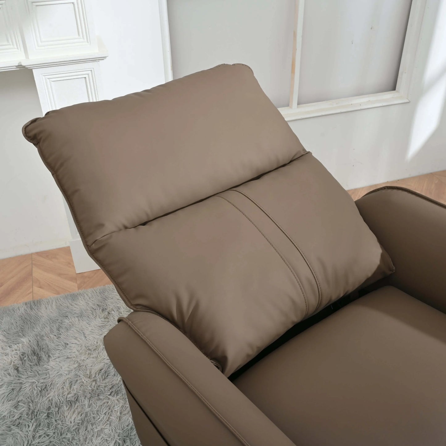 Close up of a brown recliner chair in a room with a light gray rug and white walls.
