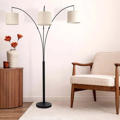 Arc floor lamp with a black stand and three white lampshades in a living room setting.