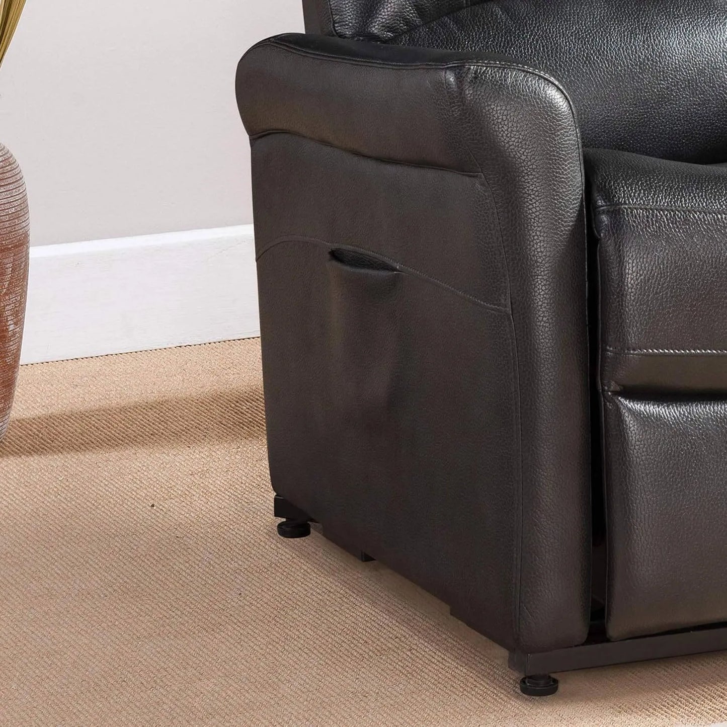 Close-up of a black faux leather recliner chair on a beige carpet.