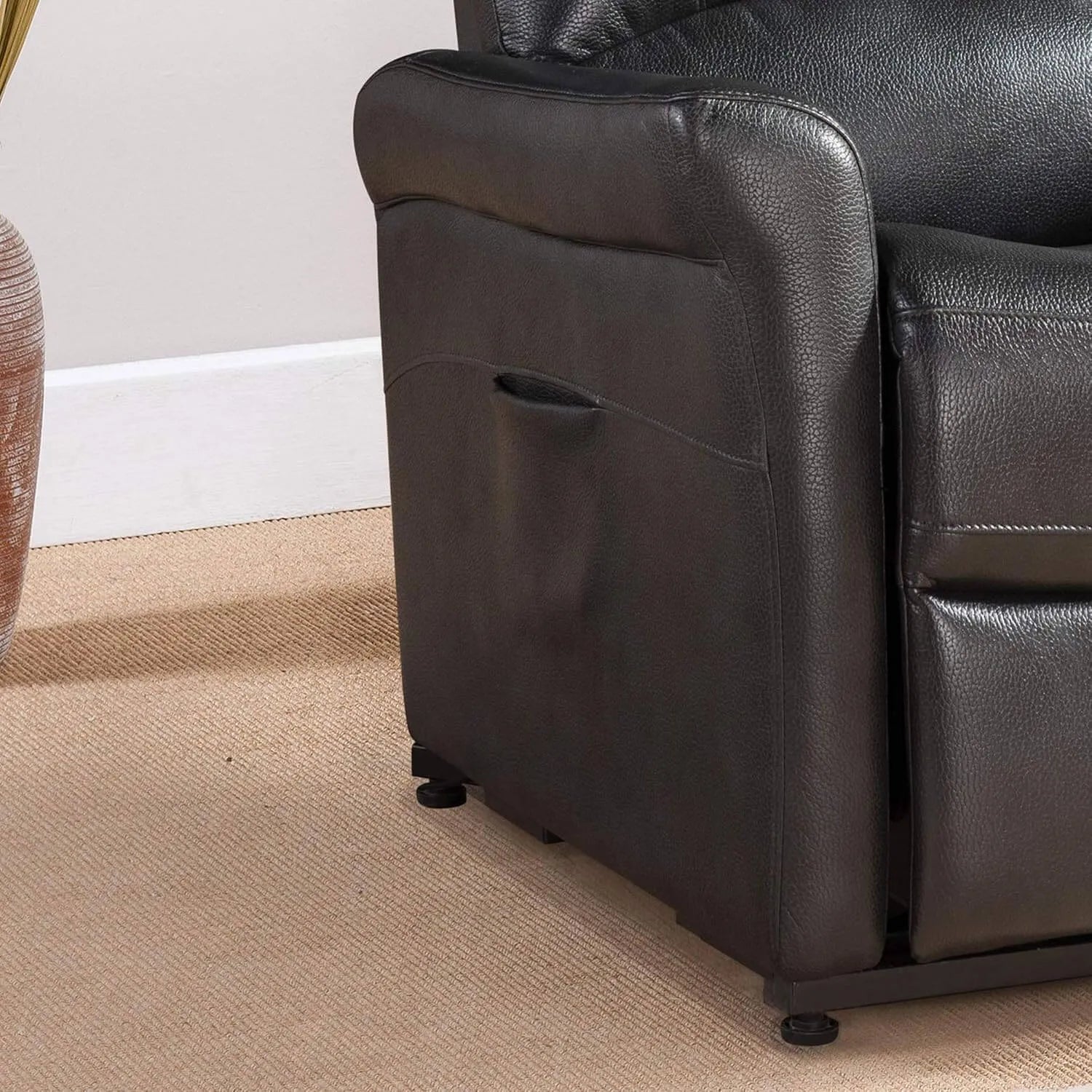 Close-up of a black faux leather recliner chair on a beige carpet.
