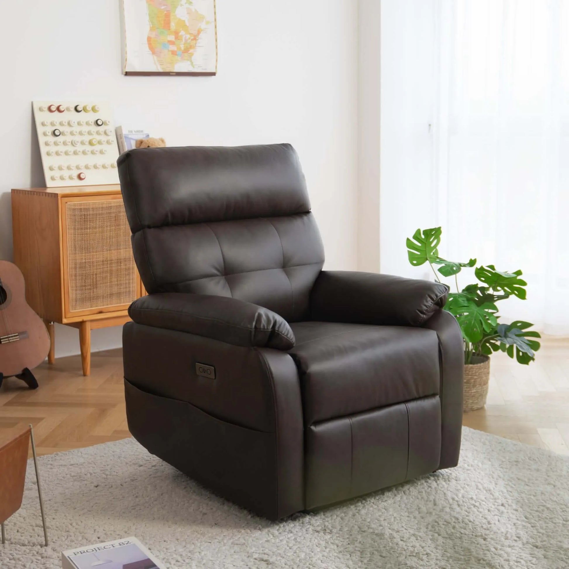 Brown leather recliner chair in a living room setting with a plant and wooden cabinet.