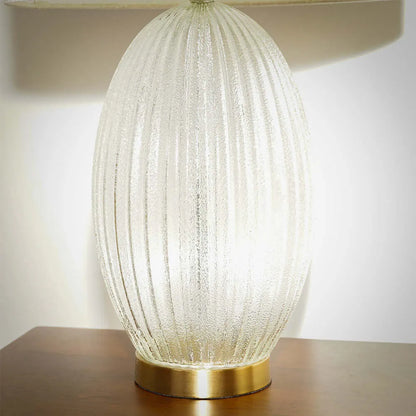 Decorative table lamp with textured glass shade on a wooden surface