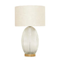 Table lamp with ribbed glass base and beige fabric shade on a white background