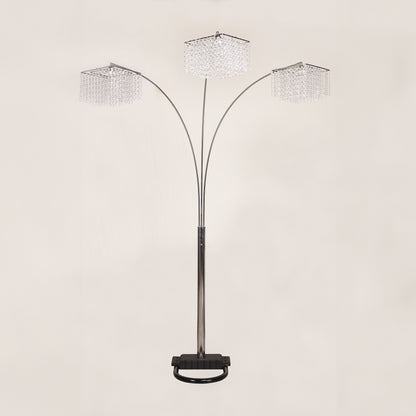 Arc floor lamp with three crystal-like shades on a beige background