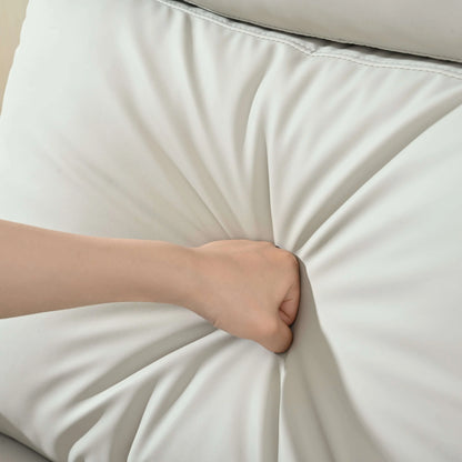 Hand punching on a light gray recliner chair top cushion to demonstrate its softness and texture.