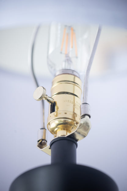Close-up of a lamp with a gold fitting and black base against a light gray background