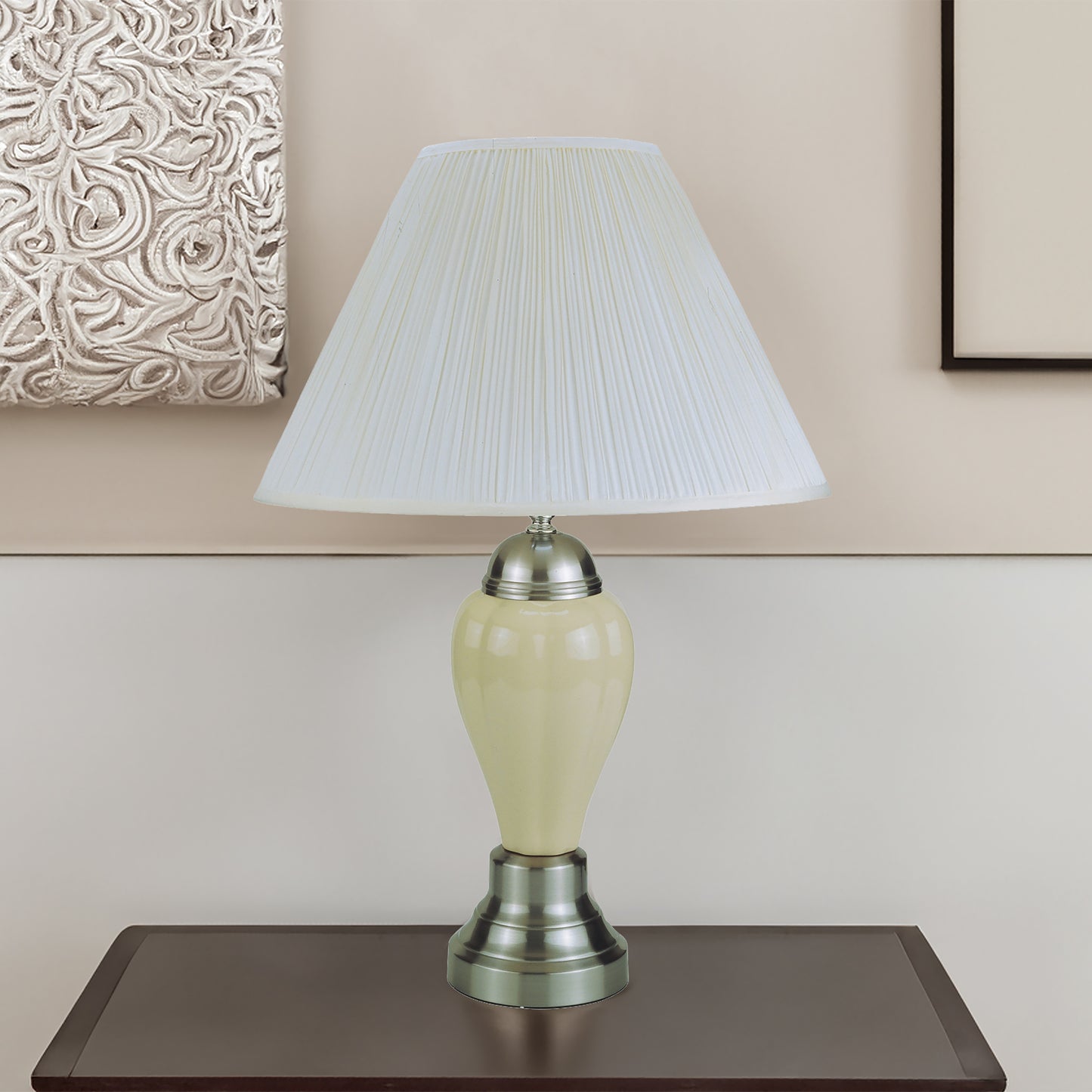 Table lamp with a white shade on a wooden surface against a beige wall.