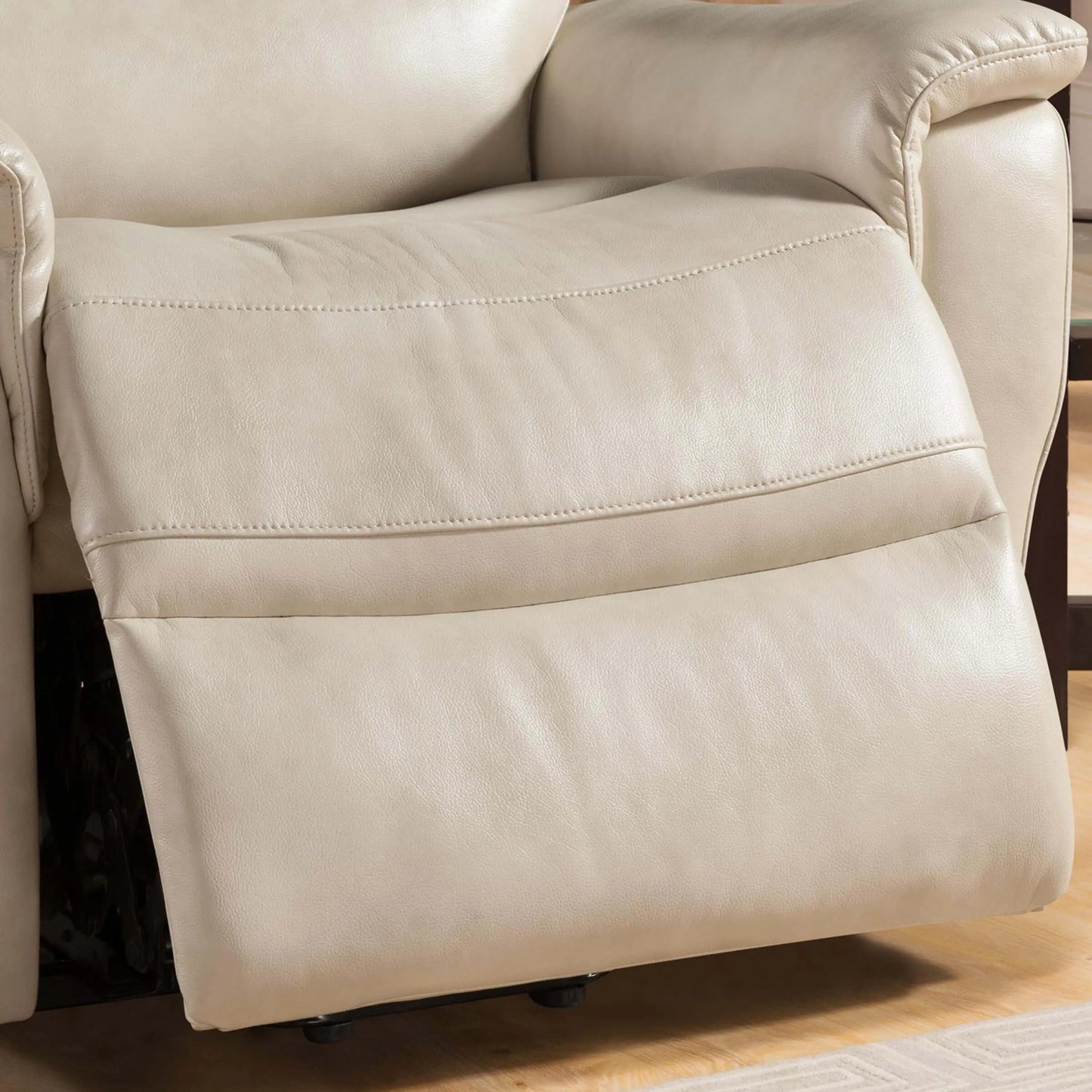 Close up of a cream color reclilner chair footrest on a wooden floor