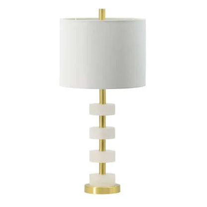 Table lamp with white shade and marble-like accents and gold base on a white background