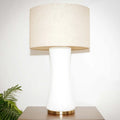 Table lamp with beige shade and white base on a wooden surface