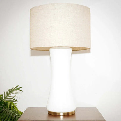 Table lamp with beige shade and white base on a wooden surface