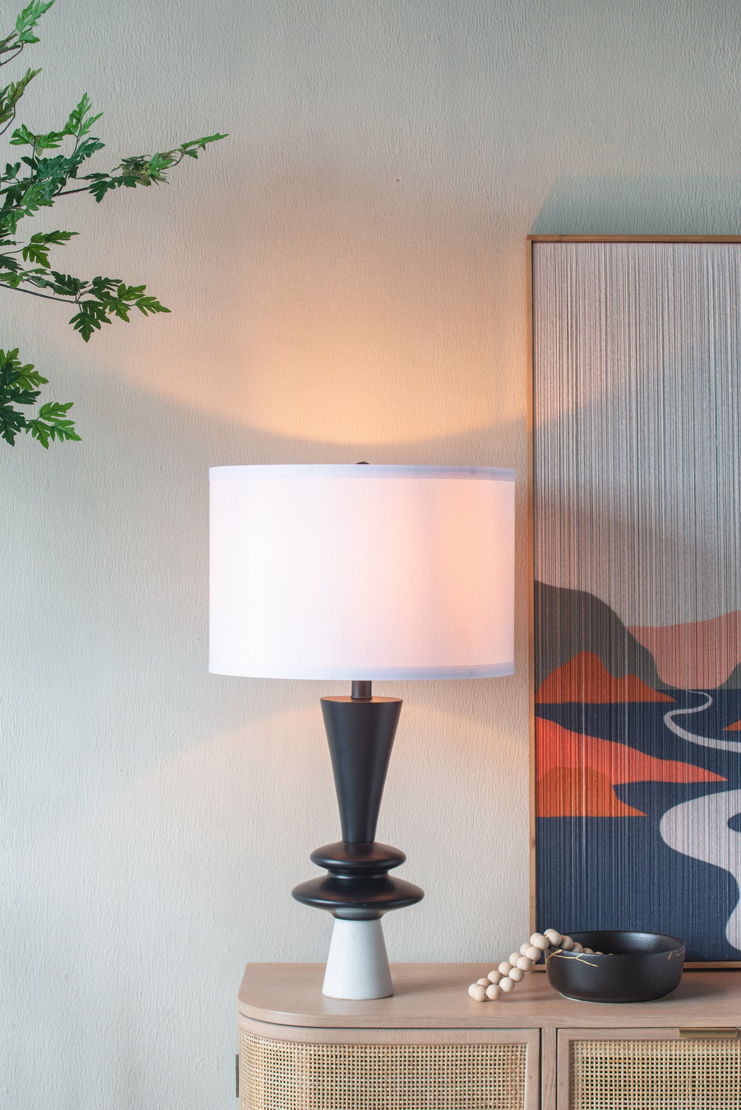 Table lamp on a side table with a decorative painting in the background