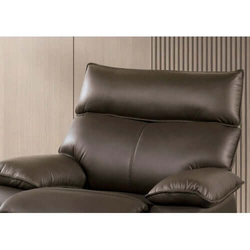 Top cushion of a brown faux leather recliner chair against a neutral wall.