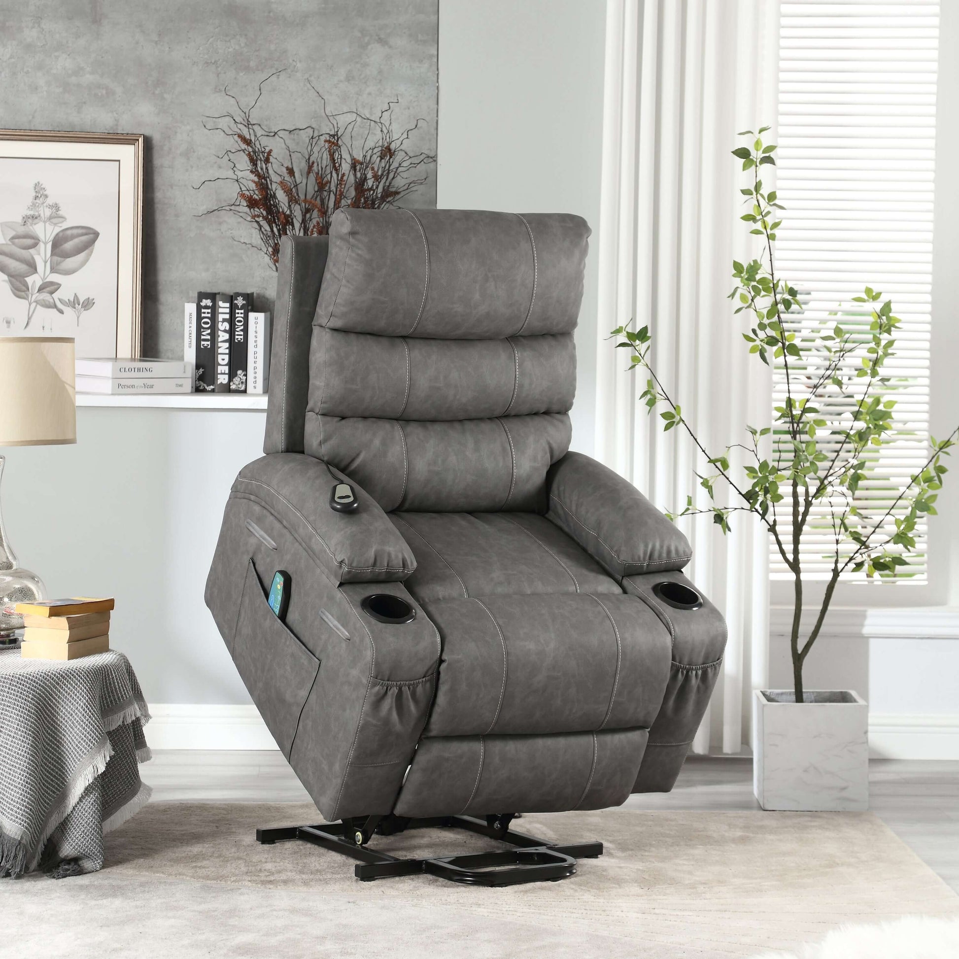 Gray faux leather power lift recliner chair in full lift position in a living room setting with table, lamp and plant