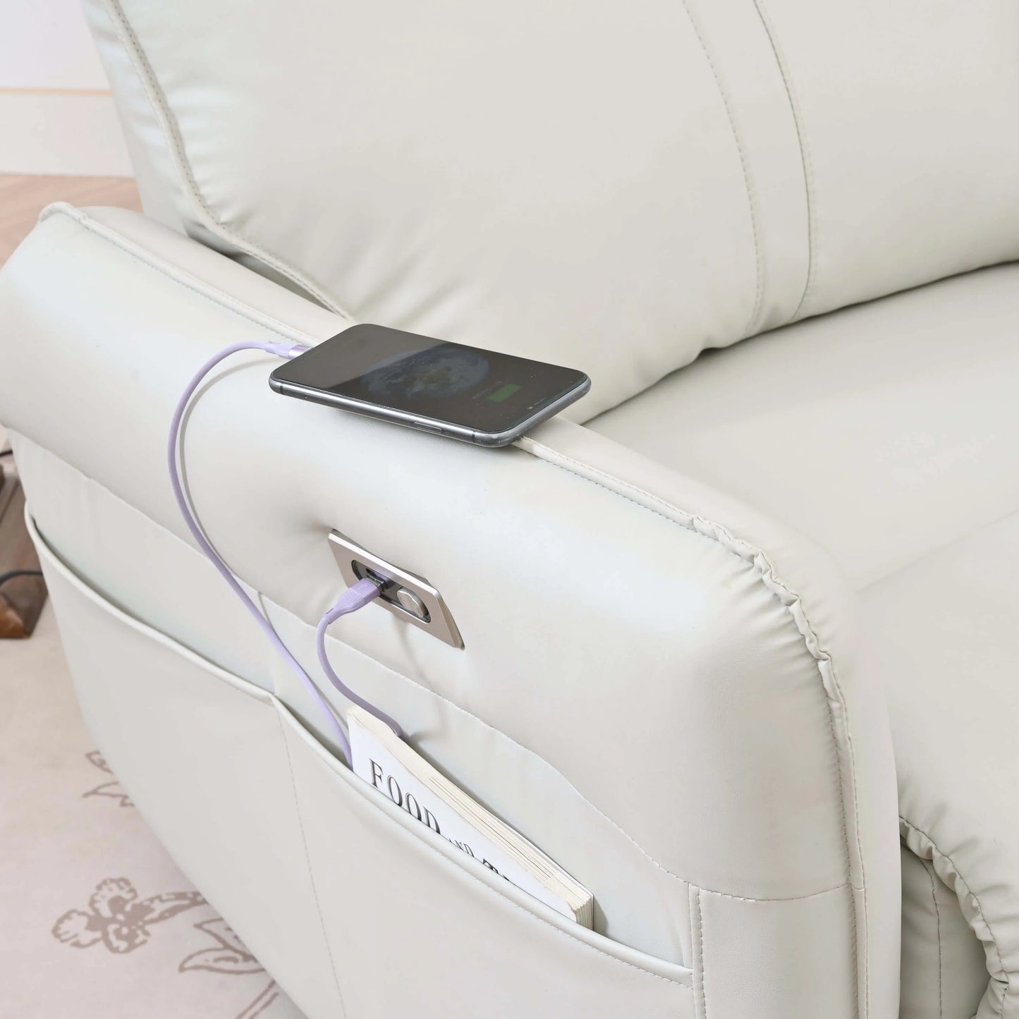Phone charging from a power bank on a light gray recliner chair