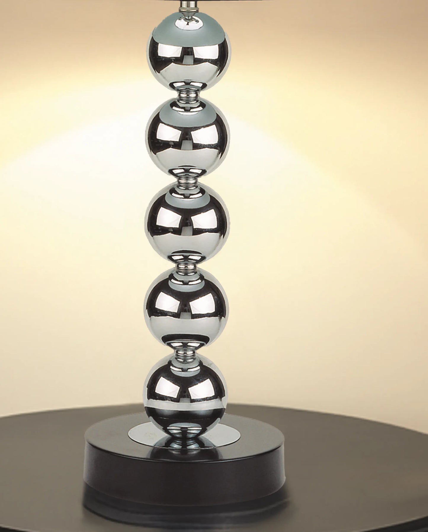 Decorative lamp base with stacked metallic spheres on a black base against a beige background