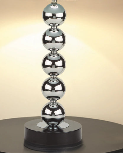 Decorative lamp base with stacked metallic spheres on a black base against a beige background