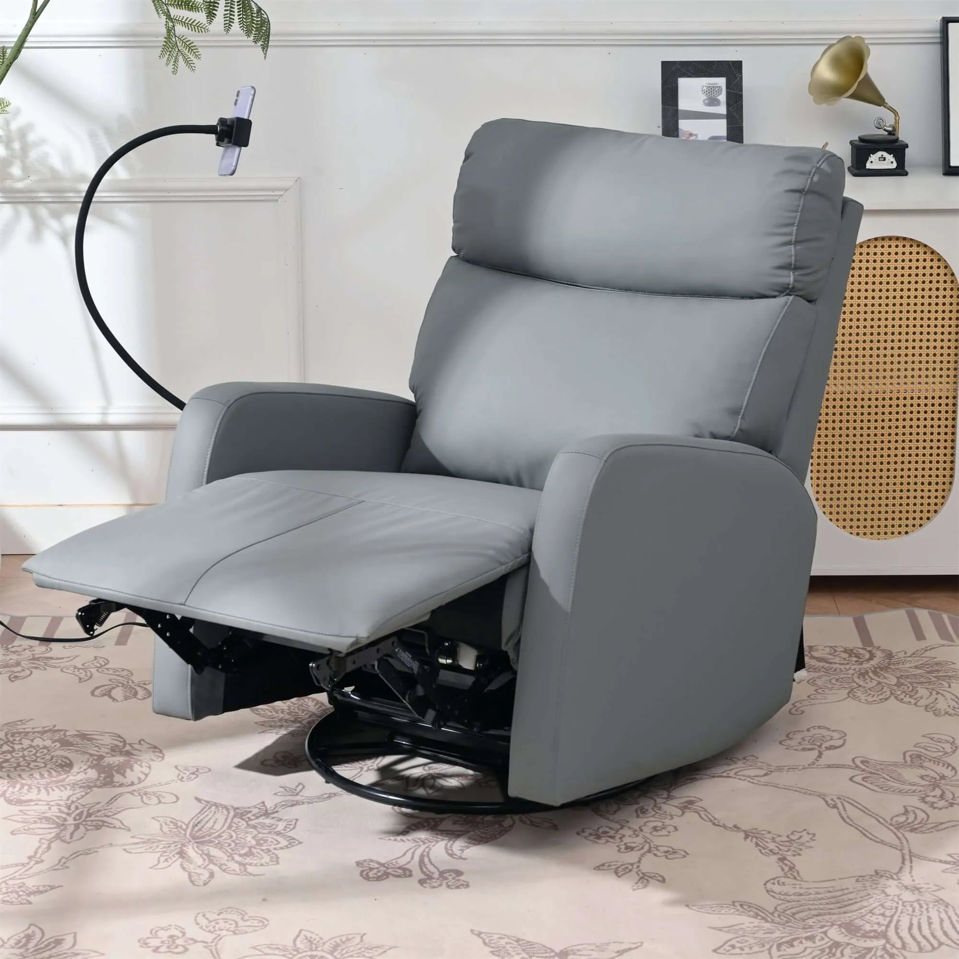 Gray leather recliner chair with footrest extended in a home setting with a plant and decorative items.