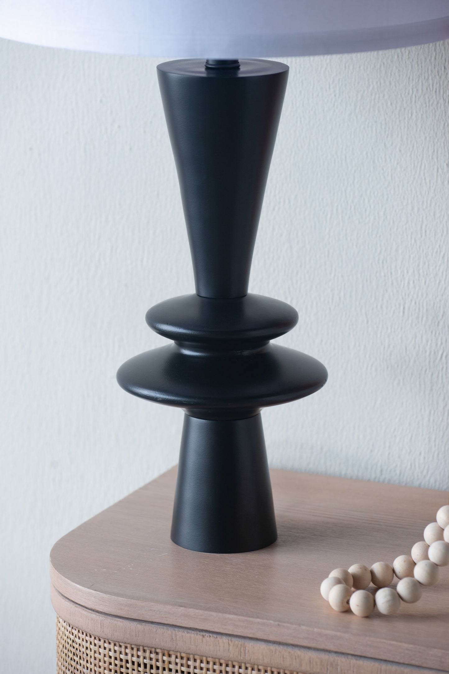 Black lamp base on a wooden surface with a white wall background