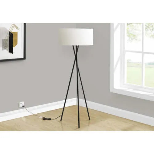 Tall floor lamp with a white shade in a room with a window and wall art.