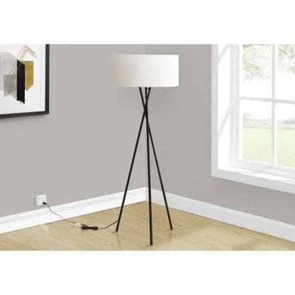 Tall floor lamp with a white shade in a room with a window and wall art.