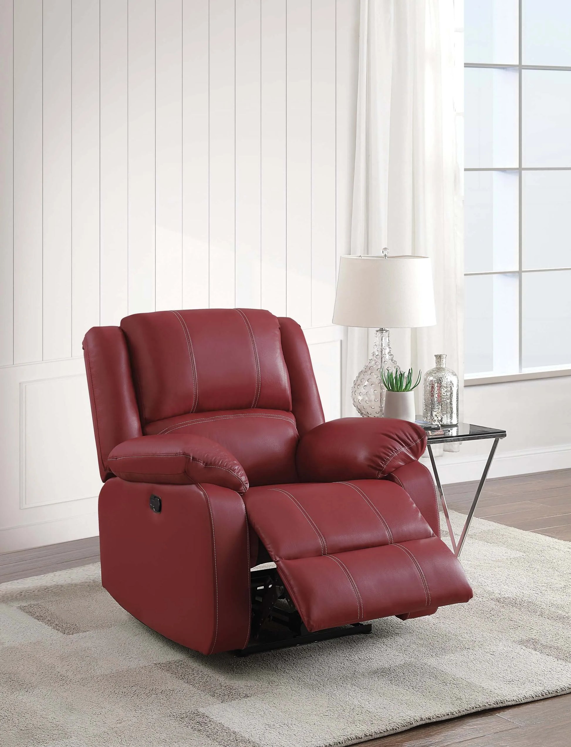 Red recliner chair in a living room setting with a lamp and decor items.