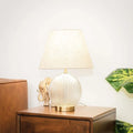 Table lamp with a ribbed glass base on a wooden surface, with a blurred background