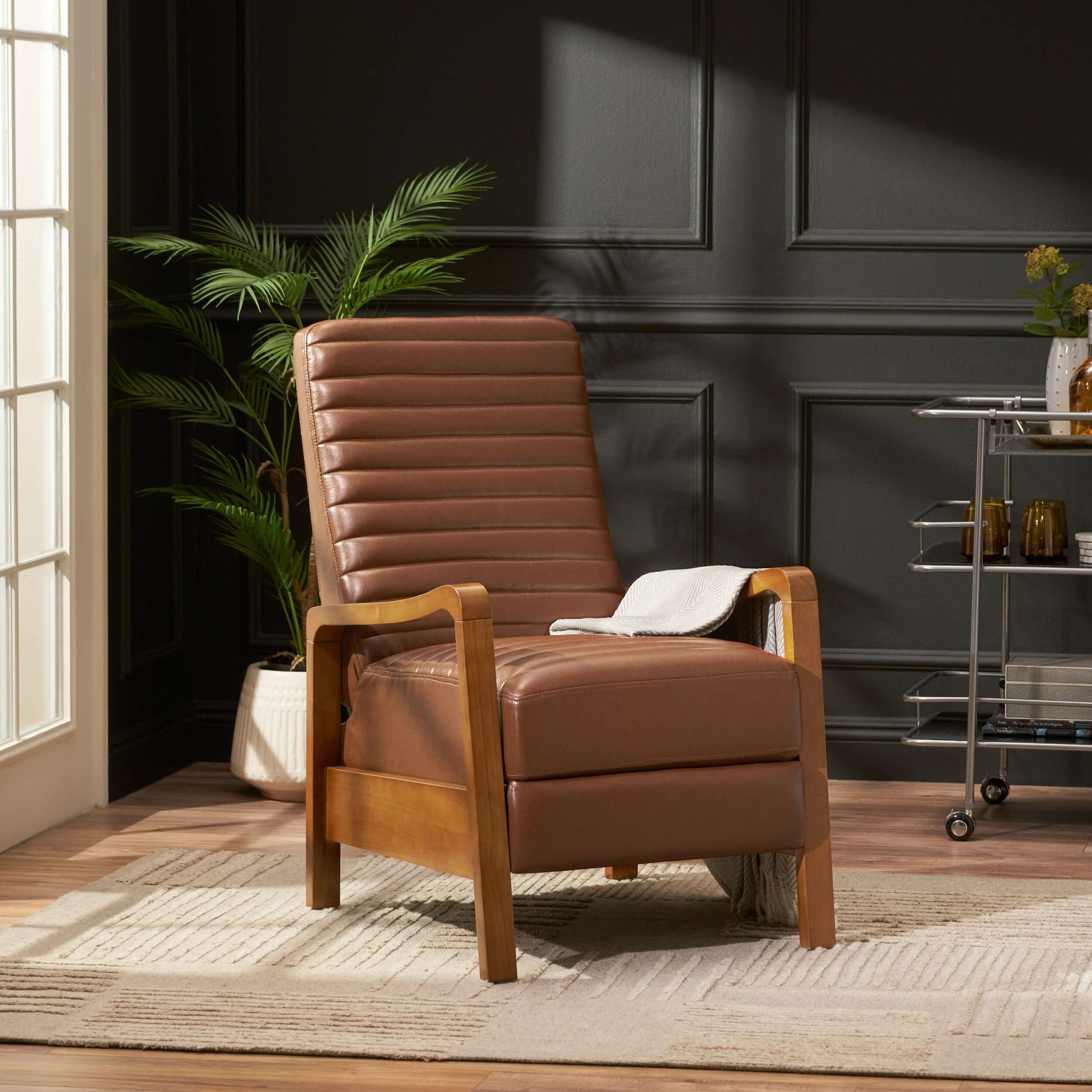Brown faux leather recliner chair in a room with dark walls and a window.